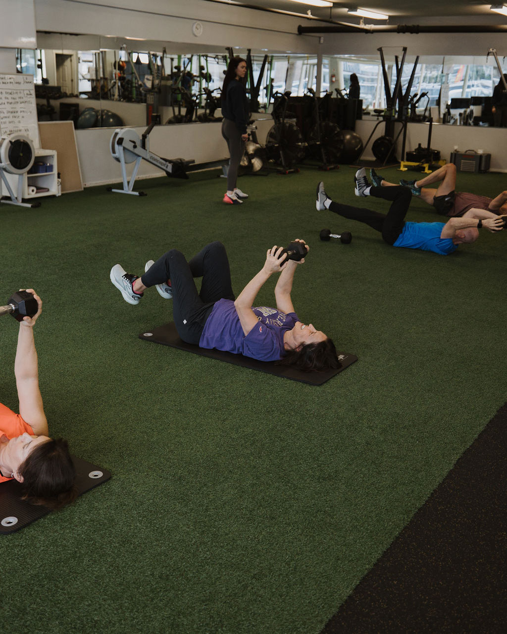 Group training class doing floor work on turf at Innovative Fitness