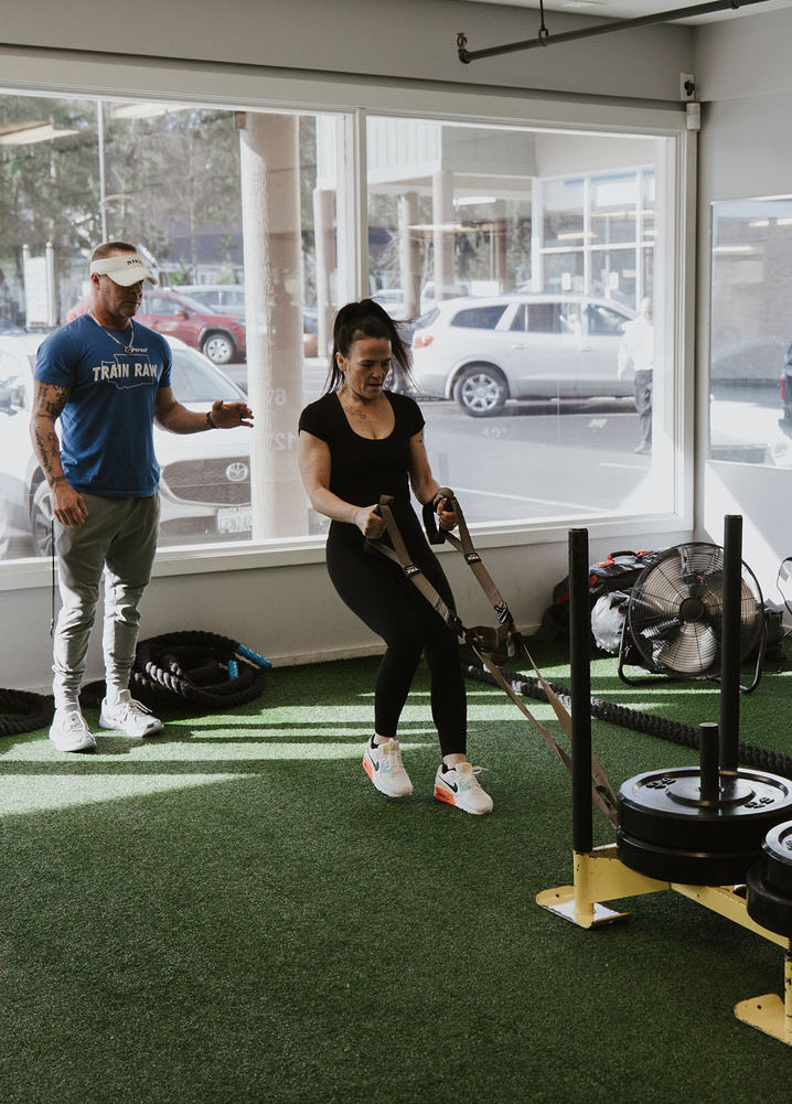 Certified trainer coaching a client through a sled push at Innovative Fitness